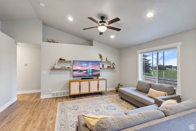 Living room featuring lofted ceiling, light wood-type flooring, ceiling fan, and recessed lighting