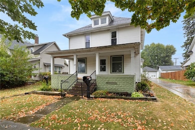 American foursquare style home with a porch, a front yard, and a garage