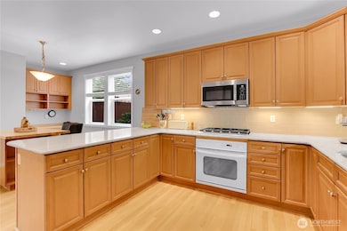 The kitchen is quite spacious and features hardwood flooring and light wood cabinetry that wraps around three walls of the kitchen, providing an abundance of storage.
