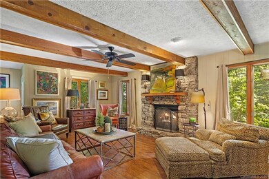 Family room with lovely stone fireplace, beamed ceiling and lots of windows