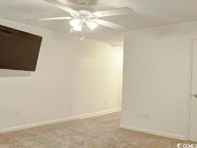 Carpeted spare room featuring ceiling fan and baseboards