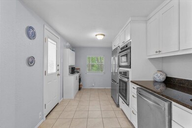 Kitchen with baseboards, white cabinetry, applian