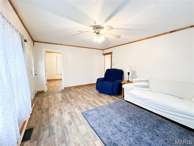 Living room featuring crown molding, wood finished floors, and ceiling fan