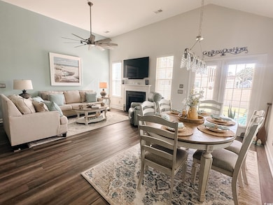 Dining room with high vaulted ceiling, wood finished floors, ceiling fan, and a fireplace