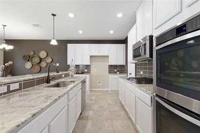 Kitchen with stainless steel appliances, decorative backsplash, white cabinets, pendant lighting, and recessed lighting