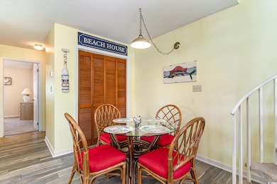 Dining area with a textured ceiling, wood finished floors, and stairs