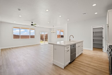 Kitchen featuring white cabinets, open floor plan, recessed lighting, a kitchen island with sink, and light wood finished floors