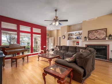 Living room with a fireplace, light wood-style floors, and ceiling fan