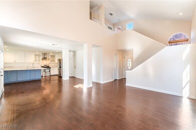 Unfurnished living room featuring dark wood-style flooring, recessed lighting, and a towering ceiling