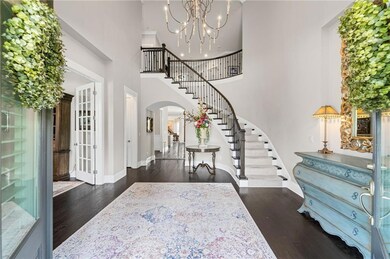 Entrance foyer featuring arched walkways, stairs, a high ceiling, wood finished floors, and baseboards