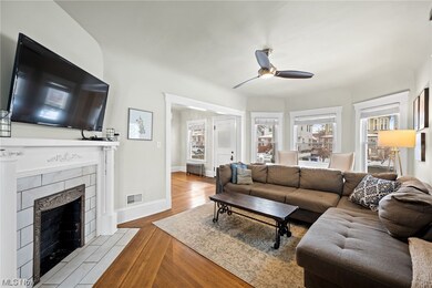 Living room featuring light wood-type flooring, a tile fireplace, and ceiling fan
