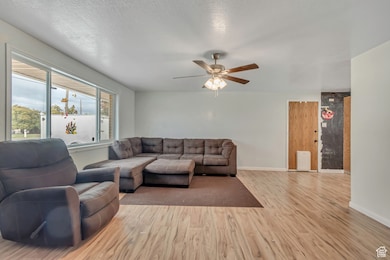Living area with light wood-style flooring, a ceiling fan, and a textured ceiling
