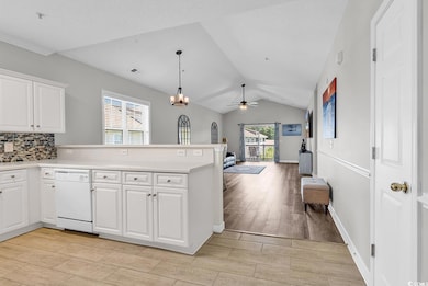 Kitchen with dishwasher, vaulted ceiling, a peninsula, open floor plan, and light wood-type flooring