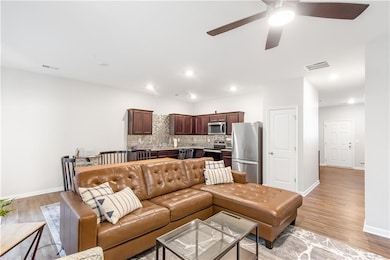 Living area with light wood-type flooring, a ceiling fan, baseboards, and recessed lighting