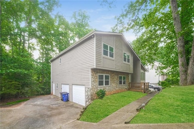 View of home's exterior with stone siding, a garage, asphalt driveway, and a yard