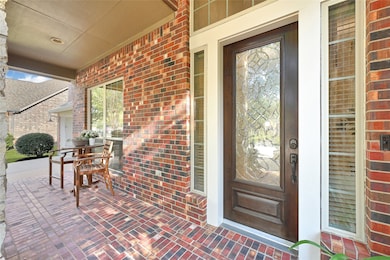 This inviting porch features a charming brick facade, a stylish glass-paneled front door, and a cozy seating area perfect for relaxing. The abundant natural light enhances its welcoming atmosphere.