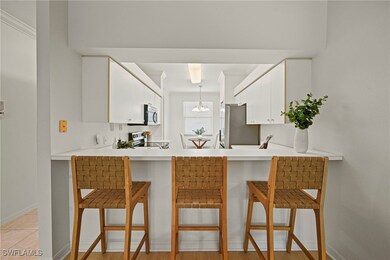 Kitchen with a kitchen bar, light countertops, white cabinetry, a chandelier, and stainless steel appliances