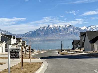 View of asphalt street with a water and mountain view, curbs, sidewalks, and street lights