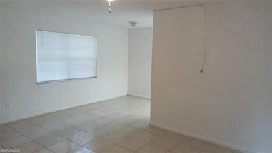 Empty room with light tile patterned flooring and baseboards