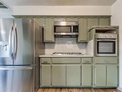 Kitchen with appliances with stainless steel finishes, green cabinetry, light countertops, and a textured ceiling