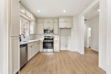 Kitchen featuring tasteful backsplash, sink, light wood-type flooring, and appliances with stainless steel finishes