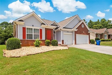 Ranch-style house featuring a garage, brick siding, concrete driveway, and a front yard