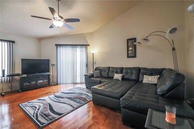 Living room with hardwood floor, ceiling fan, back slider to covered patio.