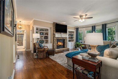 Living room featuring a ceiling fan, a stone firep