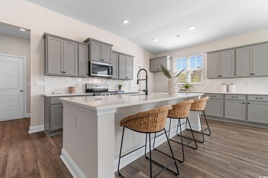 Kitchen featuring appliances with stainless steel finishes, gray cabinetry, a sink, decorative backsplash, and lofted ceiling