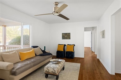 Living room featuring ceiling fan and dark hardwoo