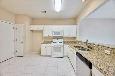 Kitchen with white appliances, a sink, light stone