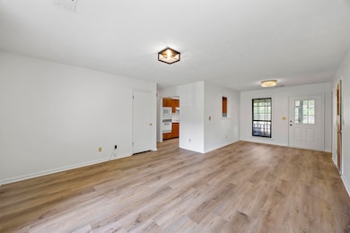 Unfurnished living room featuring light wood finished floors and baseboards
