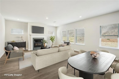 Living room featuring wood finished floors, a glass covered fireplace, and recessed lighting