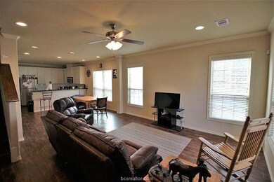 Living room with ceiling fan, crown molding, and w