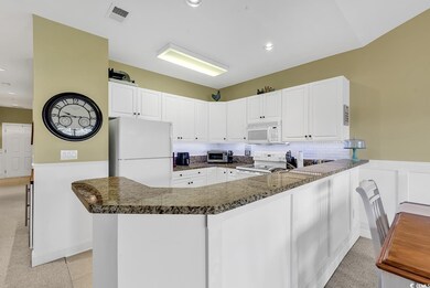Kitchen with white appliances, visible vents, wain