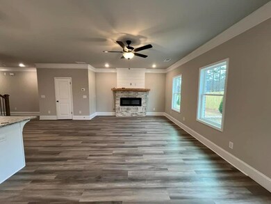 Living room featuring a brick fireplace with shiplap over mantel, a ceiling fan, baseboards, and ornamental molding