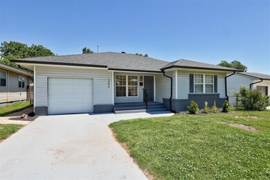 View of front of house featuring an attached garage, a front lawn, concrete driveway, brick siding, and roof with shingles