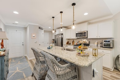 Kitchen featuring appliances with stainless steel finishes, a sink, light wood finished floors, white cabinetry, and recessed lighting