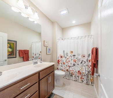 Guest bathroom has double sinks. Shower over tube. Tile plank flooring.