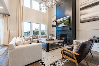 Living area featuring plenty of natural light, wood finished floors, a decorative wall, a tile fireplace, and a high ceiling