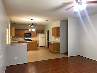 Kitchen with tasteful backsplash, brown cabinets, freestanding refrigerator, and light countertops