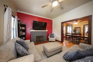 Living room featuring crown molding, hardwood / wood-style flooring, a fireplace, and ceiling fan