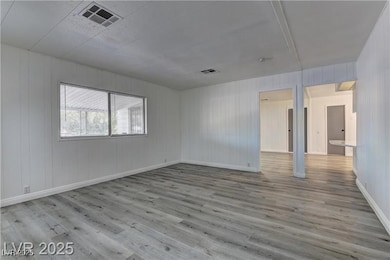 Empty room with light wood-style floors and wood walls