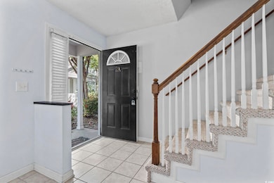 Foyer entrance with light tile patterned floors, a textured ceiling, and stairs