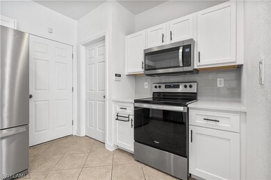 Kitchen featuring white cabinetry, tasteful backsp