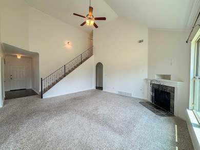 Unfurnished living room with carpet flooring, high vaulted ceiling, a fireplace, stairs, and ceiling fan