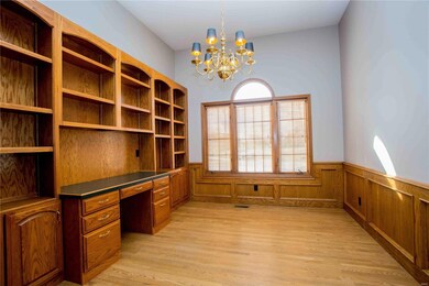 Office has wall of built ins and hard wood floors