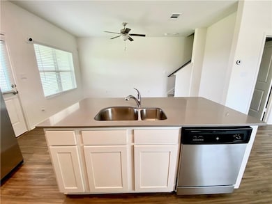 Kitchen with a kitchen island with sink, white cabinetry, stainless steel appliances, and dark wood-style flooring
