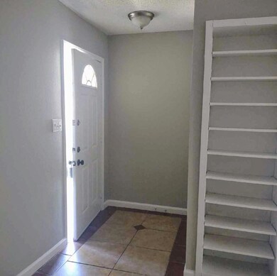 Tiled entrance foyer with baseboards and a textur