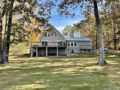 Rear view of property with a metal roof, a yard, and a wooden deck